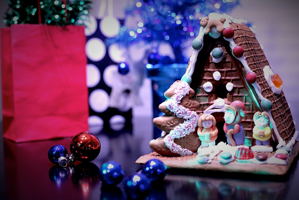 A gingerbread house with small models of people outside it.